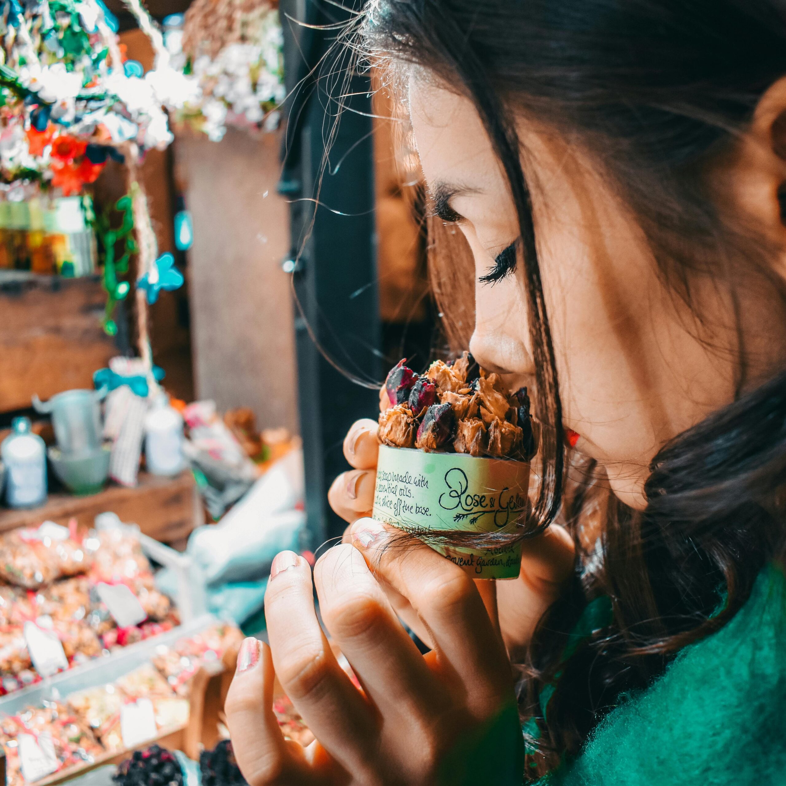 A woman savoring the scent of potpourri at a vibrant London market, capturing the essence of street life.